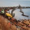 Reclaiming pulpwood from a barge that tipped during rough weather at sea. The excavator is equipped with a fixed grapple that allows for horizontal controlled movements and increases manoeuvrability.